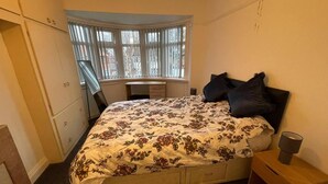 Un dormitorio con una cama, un escritorio y una ventana.