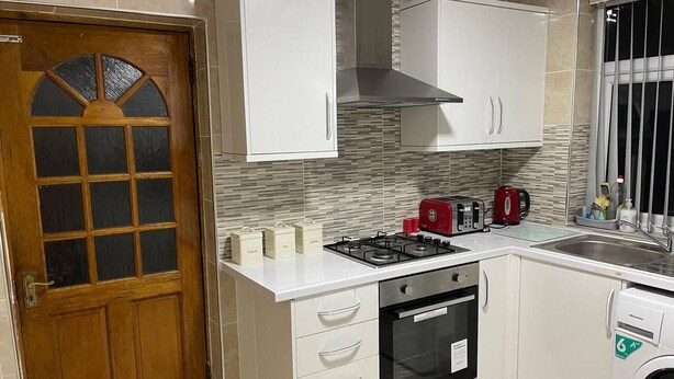 Una cocina compacta con armarios blancos, horno empotrado, cocina a gas y lavadora.