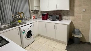 Una cocina compacta con lavadora, microondas y armarios.