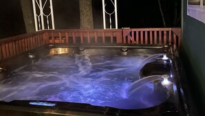 Un bain à remous avec une structure extérieure en bois et des garde-corps en métal.