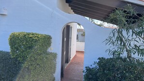 A white building with a covered walkway and a small archway.