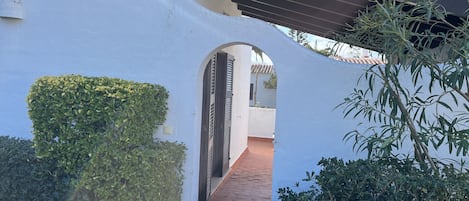 Un edificio blanco con un paseo techado y un pequeño arco.