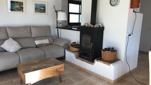 A living room with a sofa, a wooden coffee table, a fireplace, and two framed pictures on the wall.