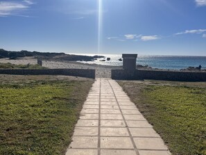 Ein Weg, der zu einem Strand führt, gesäumt von Steinmauern.