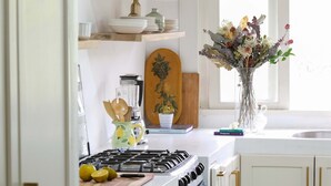 Una cocina con armarios blancos, estufa a gas, pileta y ventana que proporciona luz natural.