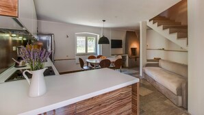 Une cuisine moderne avec un plan de travail blanc, des éléments en bois et un coin repas comprenant une table ronde et des chaises.