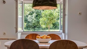 Un coin repas avec une table, des chaises et un saladier rempli d’oranges.
