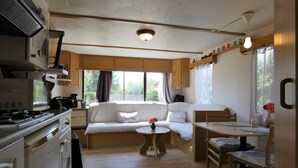 A compact living space with a kitchenette, a sofa, a dining table, and a small window. - Bungalow on a horse farm (Yèvres)