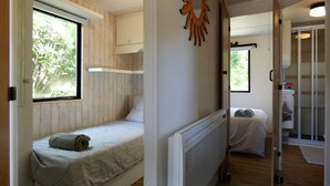 A compact room with a bed, a window, a radiator, and a door leading to another room. - Bungalow on a horse farm (Yèvres)