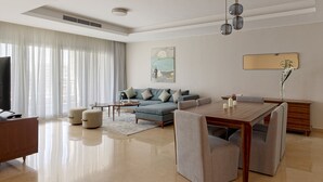 Una sala de estar moderna con un sofá, una mesa de comedor, sillas, un televisor y un cuadro en la pared.