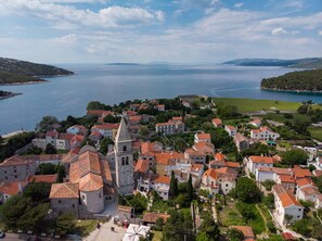 A coastal town with a prominent church, surrounded by residential buildings and a large body of water. - Impeccable 4-bed Apartment in Osor (Mali Losinj)
