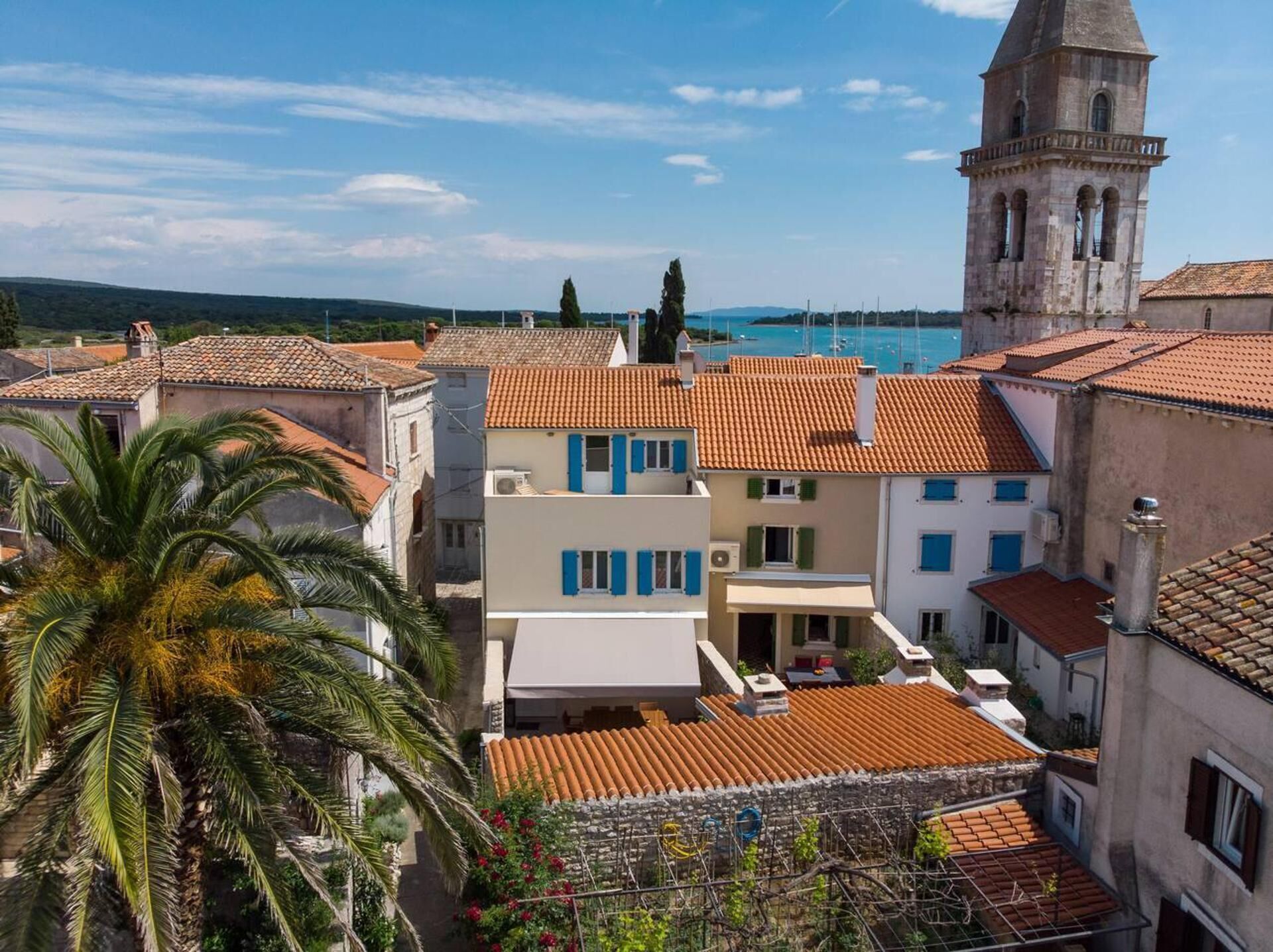 A coastal town with traditional architecture, including a prominent tower and terracotta-roofed buildings.