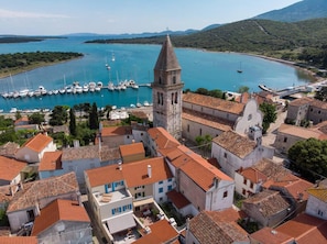 A coastal town with a prominent church tower, a marina with boats, and terracotta-roofed buildings. - Impeccable 4-bed Apartment in Osor (Mali Losinj)