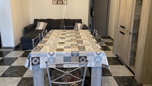 Een eethoek met een geruit tafelkleed, een bank en een kast.