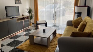 Een woonkamer met een bank, salontafel, televisie en een plant.