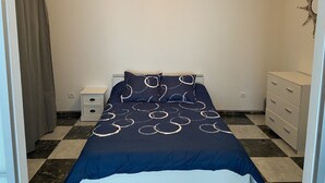Een slaapkamer met een bed, nachtkastje, kaptafel en decoratieve wanddecoratie.