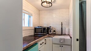 A compact kitchen with white cabinets, a microwave, a coffee maker, and a sink. - Cozy Cabin in a rural setting #10 In Temple, NH (Temple)