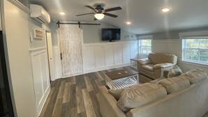 A spacious living area with a large sofa, a coffee table, and a ceiling fan. - 4-minute walk to beautiful Emerald Isle beach access. (Emerald Isle)
