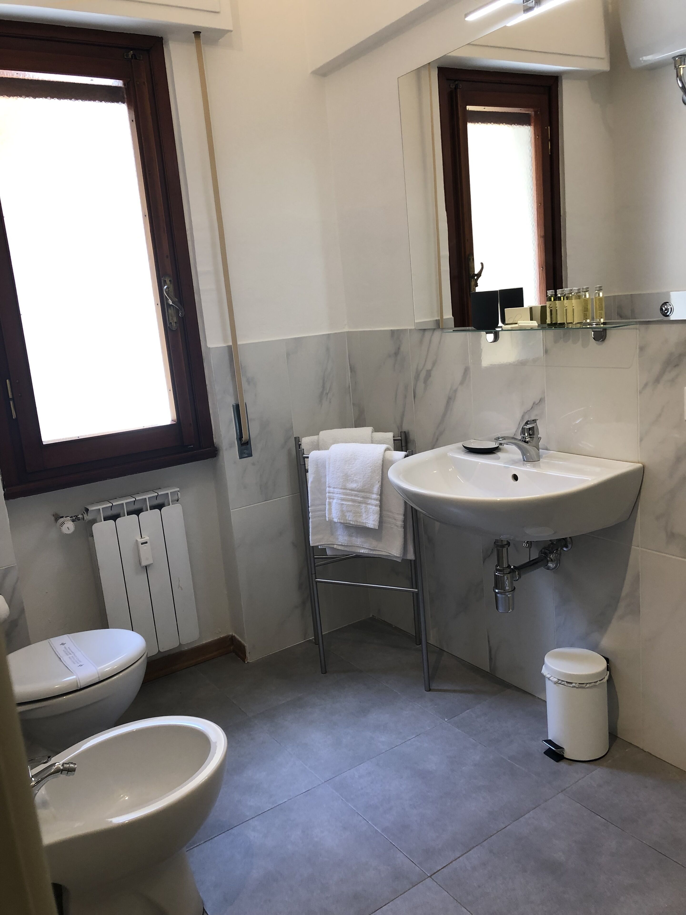 A bathroom with a toilet, bidet, sink, and a towel rack.