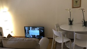 A living room with a television, a dining table with chairs, and a sofa. - Oro Mono (Florence)