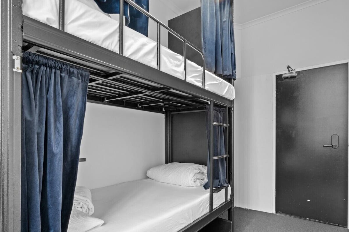A bunk bed room with a door and curtains.