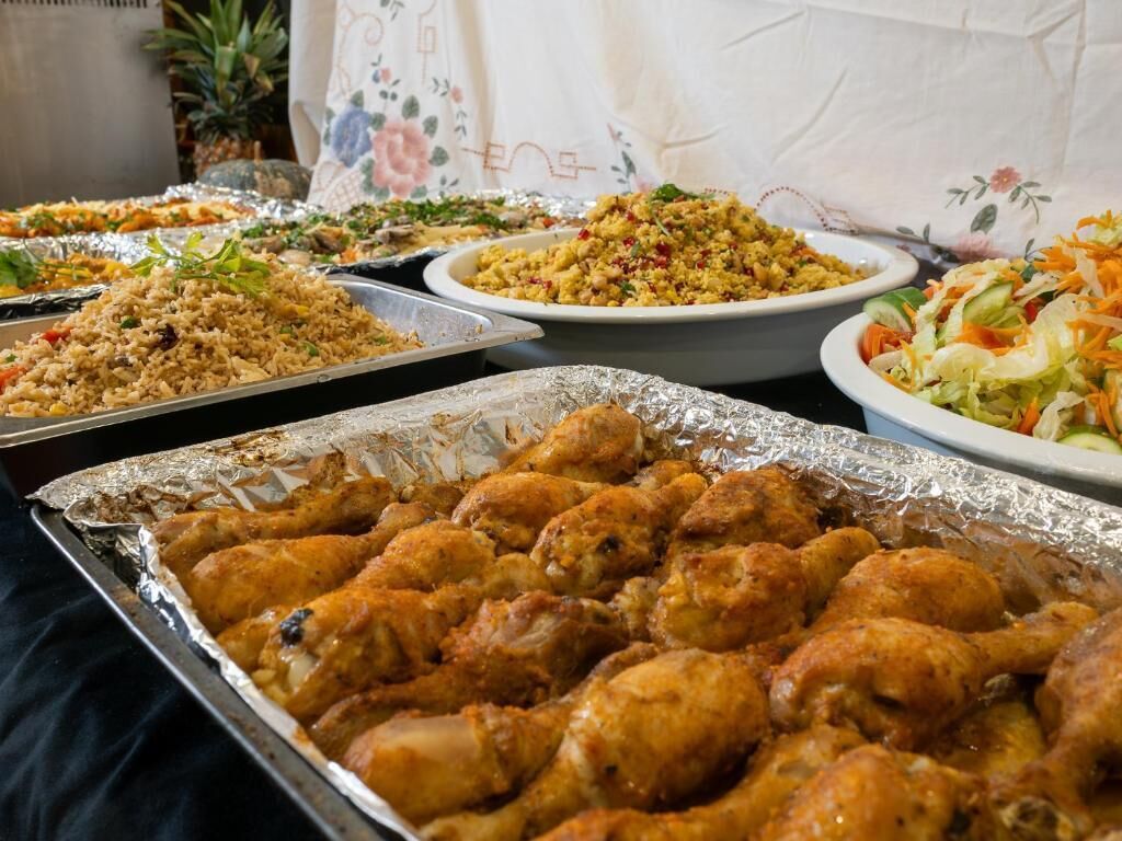 A buffet table with various dishes including fried chicken, rice, and salads.