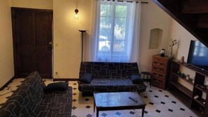 En stue med sofa, sofabord, fjernsyn og trappe.