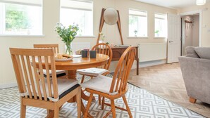 A dining area with a round table, wooden chairs, a vase with flowers, and a ceiling light fixture.