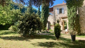Una casa de piedra con jardín, rodeada de árboles y vegetación.