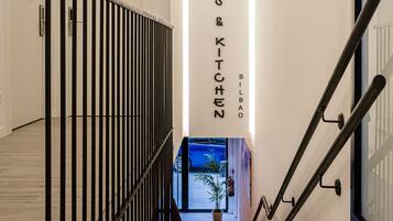A modern staircase with black railings and a sign reading "ZOS & KITCHEN" in a hallway with white walls and wooden flooring.
