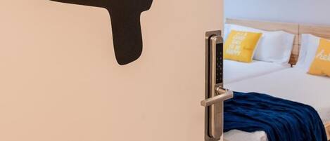 A room with a bed, a door with a large number 4, and a colorful artwork above the bed.