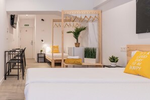 A hotel room with a bed, a desk, a chair, a hanging clothes rack, and a potted plant. - Bilbao ROOMS & KITCHEN Zorroza (Bilbao)