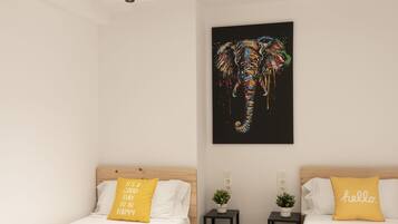 Een moderne hotelkamer met twee enkele bedden, een dakraam, een kunstwerk van een zwarte olifant en kleine potplanten.