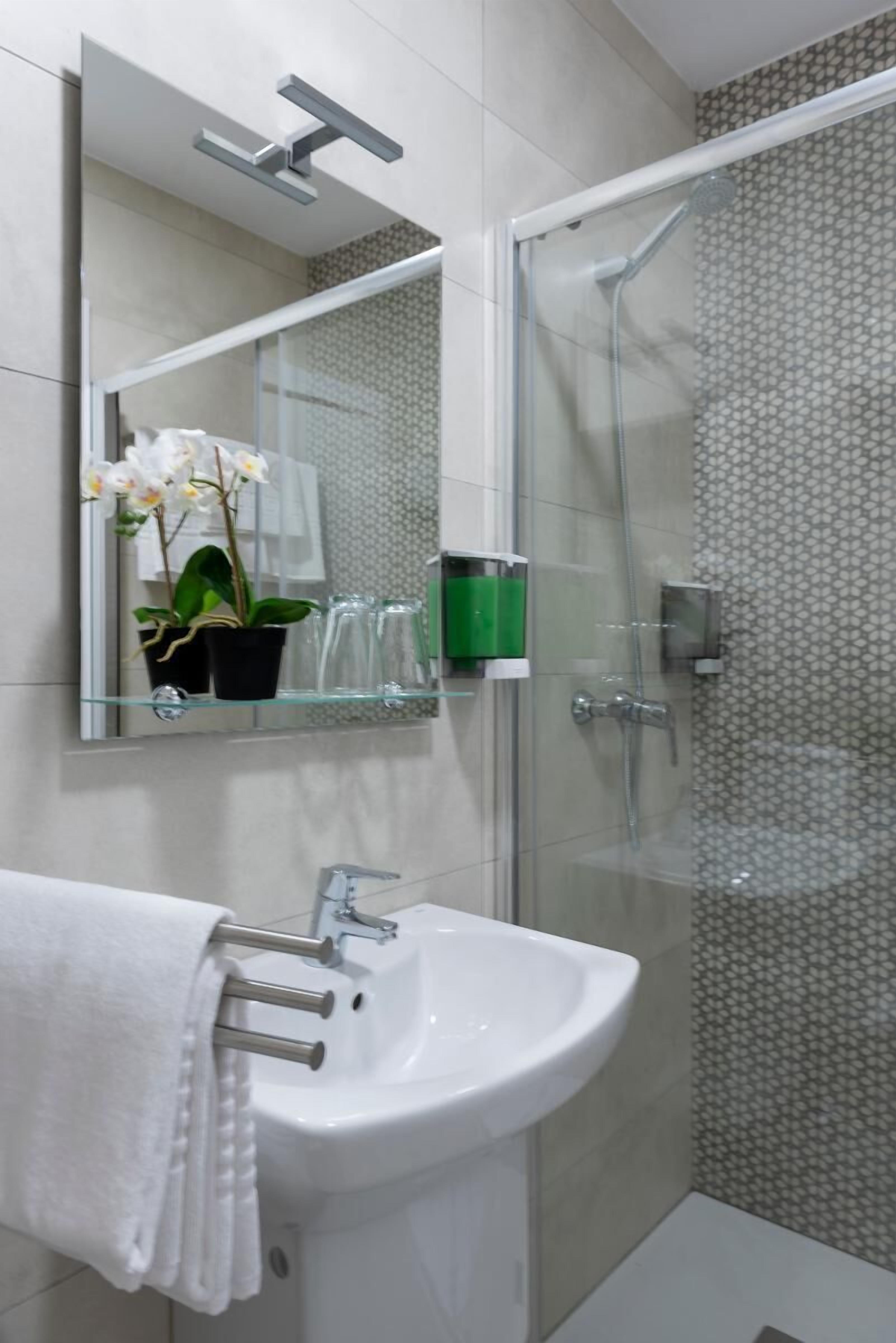Un baño moderno con cabina de ducha de vidrio, un lavabo blanco y un espejo sobre el lavabo.