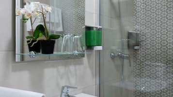 Un baño moderno con cabina de ducha de vidrio, un lavabo blanco y un espejo sobre el lavabo.