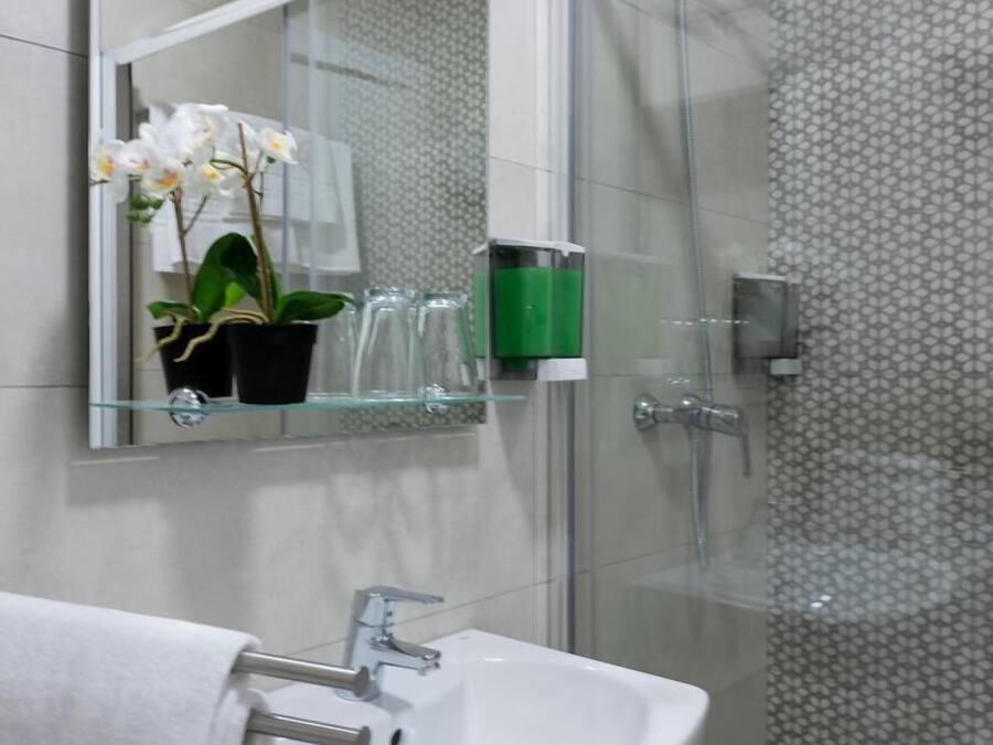 Un baño moderno con cabina de ducha de vidrio, un lavabo blanco y un espejo sobre el lavabo.