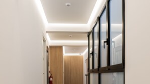 A modern hallway with a wooden floor, glass doors, and a ceiling light fixture. - Bilbao ROOMS & KITCHEN Zorroza (Bilbao)