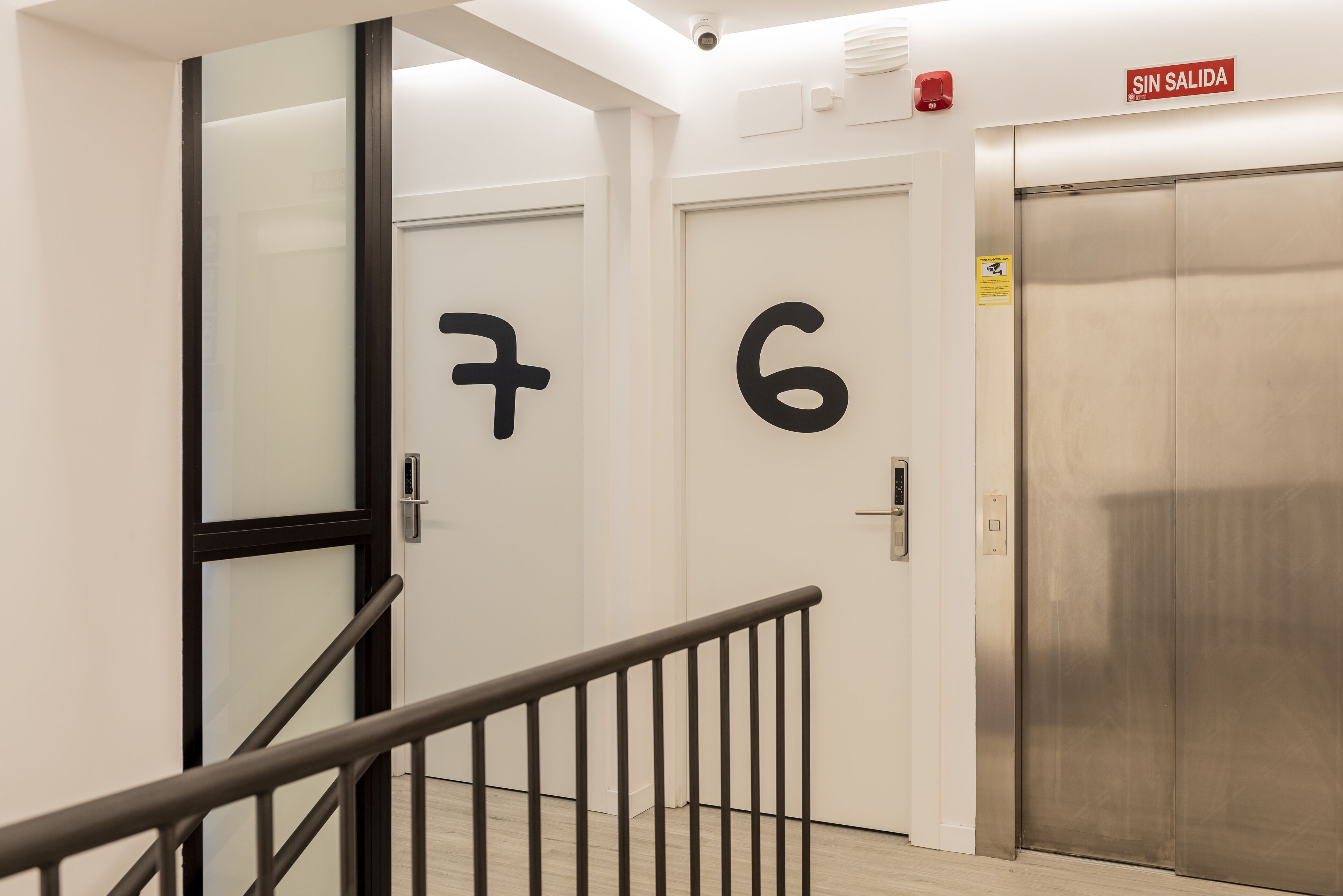 Un couloir avec des portes numérotées 7 et 6, un escalier et un ascenseur.
