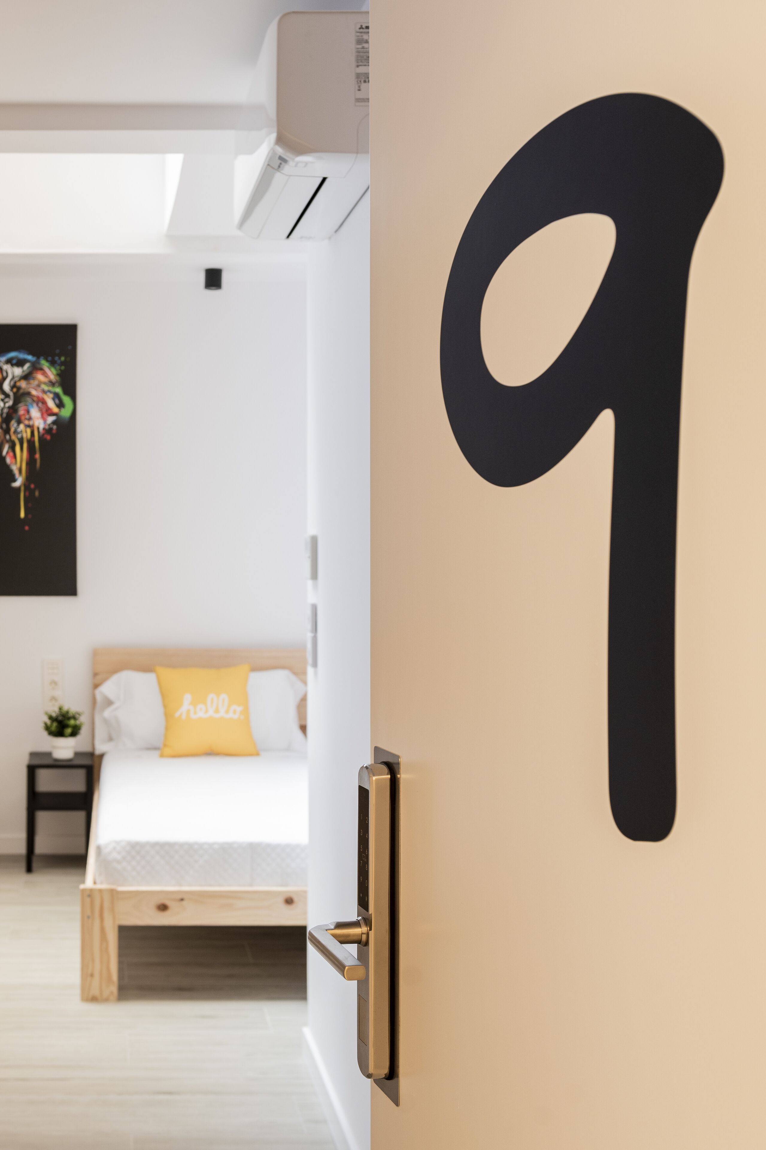 Un dormitorio con una cama, una mesita de noche y el número 9 sujeto a la pared.