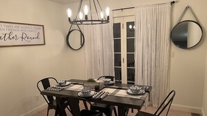 Un comedor con una araña, un espejo y un cartel en la pared.