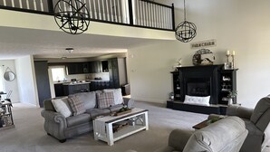 Un salón amplio con un sofá gris, una mesa de centro y una chimenea.