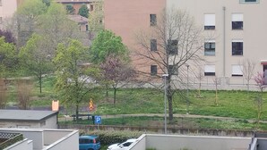 A residential area with a parking sign, a blue car, and a building with multiple windows.
