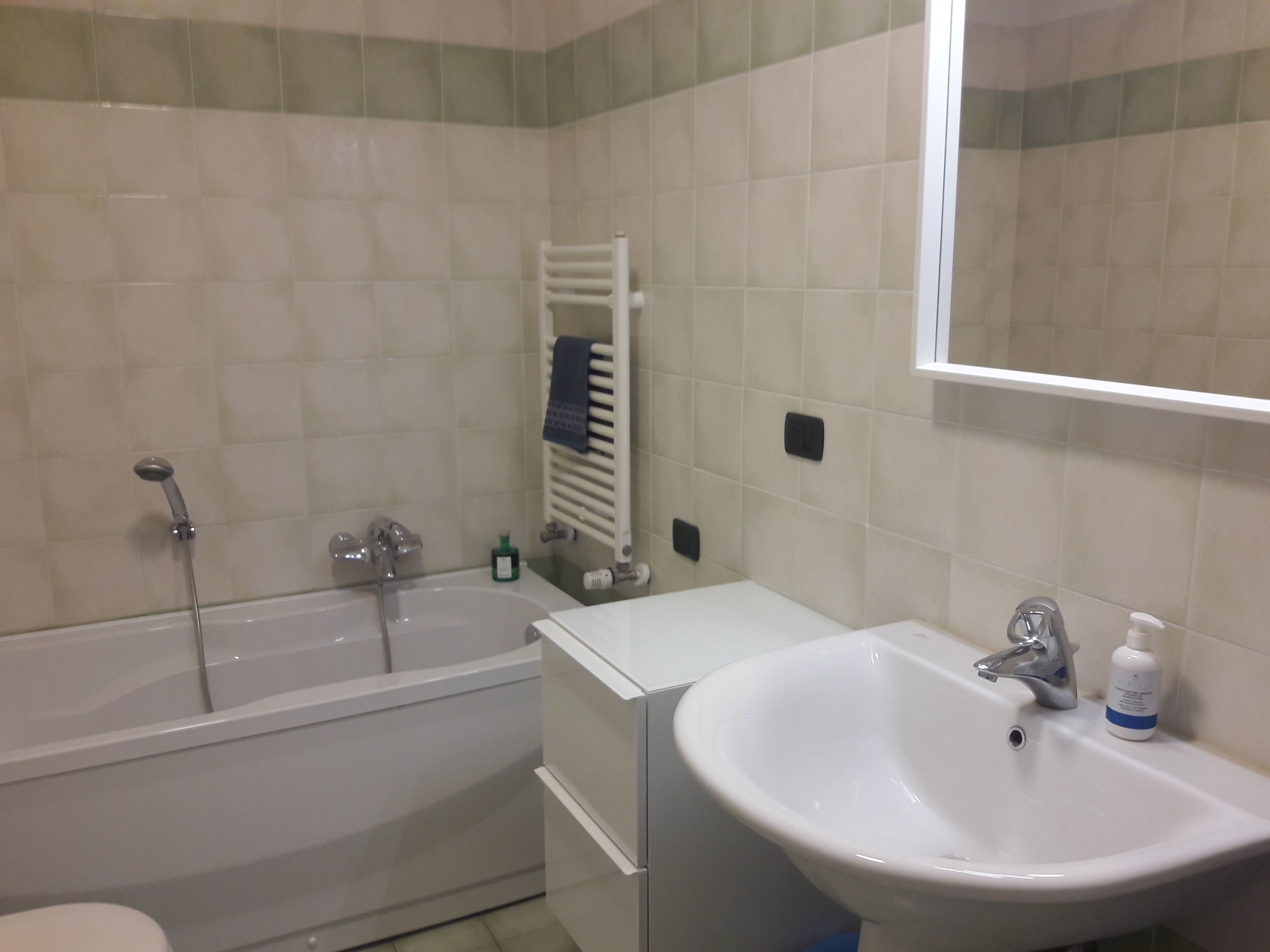 A bathroom with a bathtub, a sink, and a mirror.