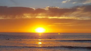 Un coucher de soleil sur l’océan, avec un ciel dégagé et une mer calme.