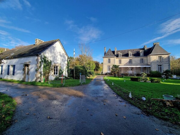 A rural road leading to a large stone house with a white facade and a grey roof. - Gite - 800 m from the sea & commodities in a parc of  3,5ha for familly event -  (Loctudy)