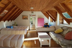 Cozy attic bedroom with two beds, a bench, and a couch, offering a welcoming space to rest.