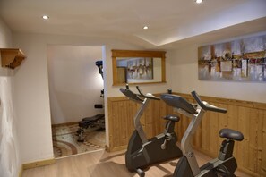 A gym with two stationary bikes, wooden walls, a mirror, and a painting.