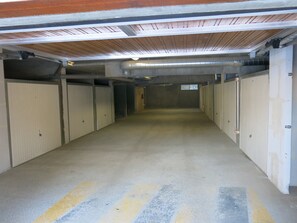 A long, narrow hallway with metal lockers on both sides and a concrete floor.