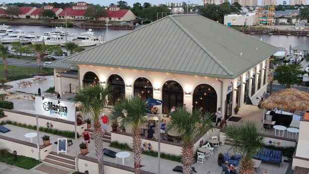 A waterfront restaurant with outdoor seating, a covered patio, and a view of boats and water. - XXXXXXXXXX (North Myrtle Beach)