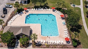 An aerial view of a swimming pool surrounded by lounge chairs and umbrellas, with a building adjacent to the pool. - XXXXXXXXXX (North Myrtle Beach)